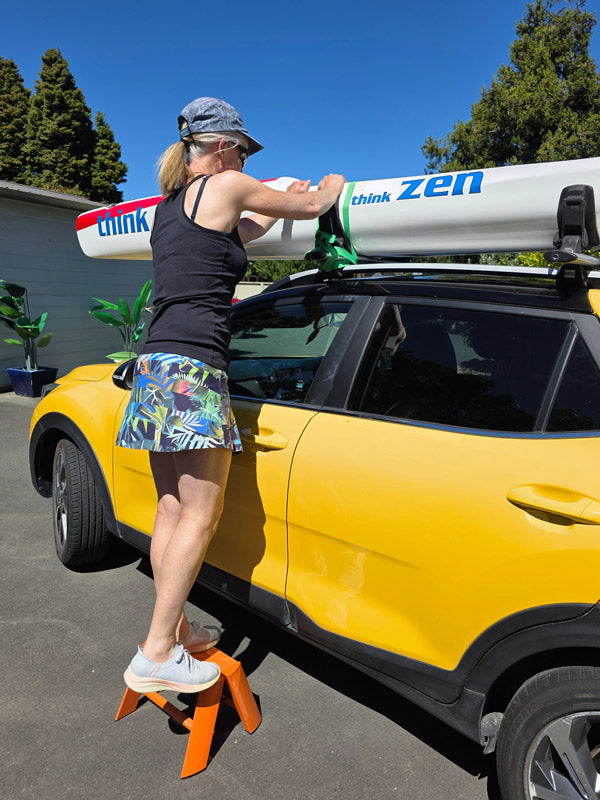 Lifting kayak on car roof rack whilst standing on a Lucano step stool